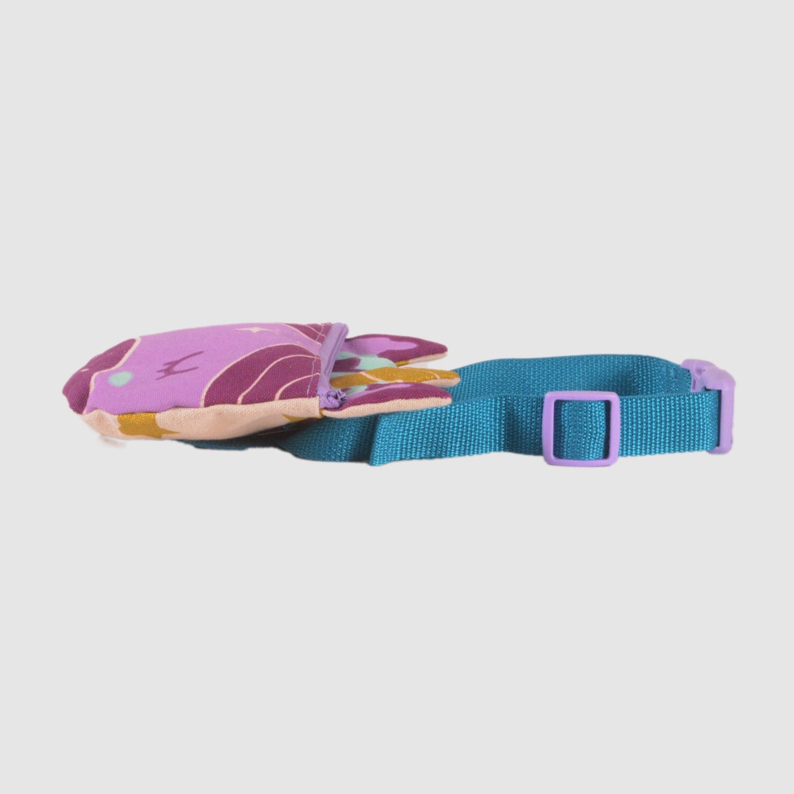 View of a Lovelane 'unicorn belt bag' laying on its side, on a light grey background