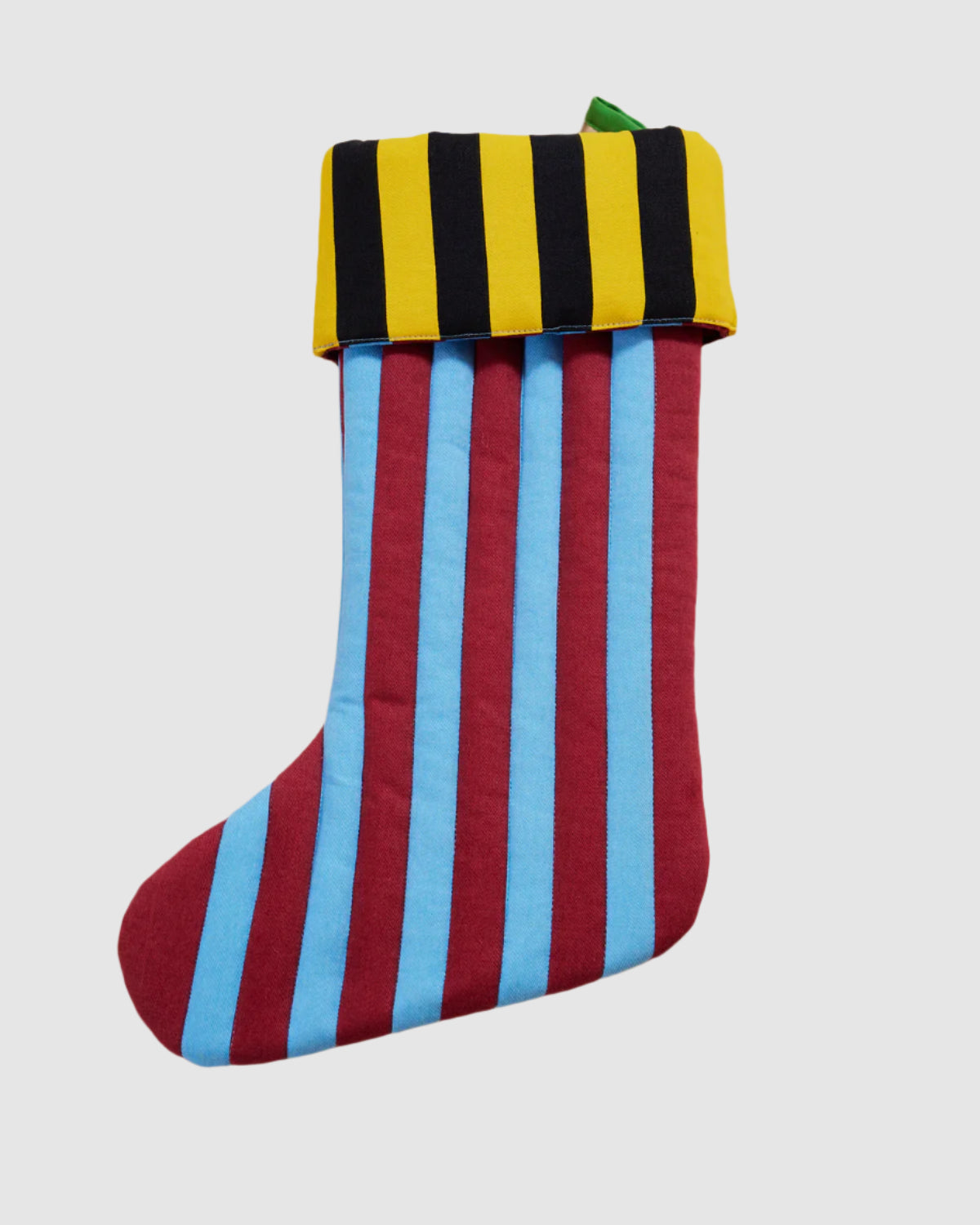 Front view of a quilted cotton holiday stocking with fabric loop for hanging. Striped, multi colored pattern on each featuring light blue, dark red, yellow, and black.