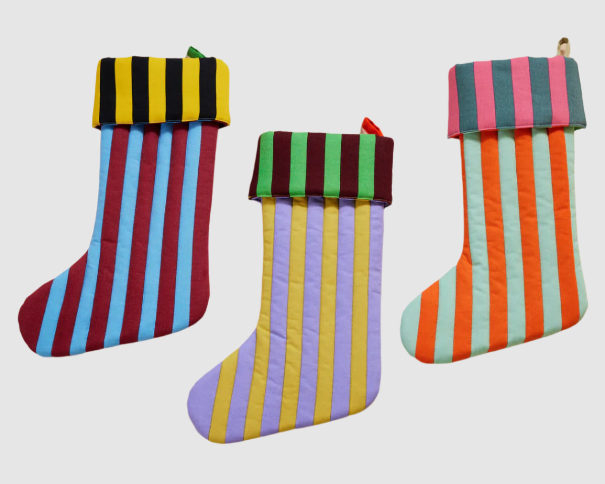 Front view of 3 quilted cotton holiday stockings with fabric loop for hanging. Striped, multi colored pattern on each.