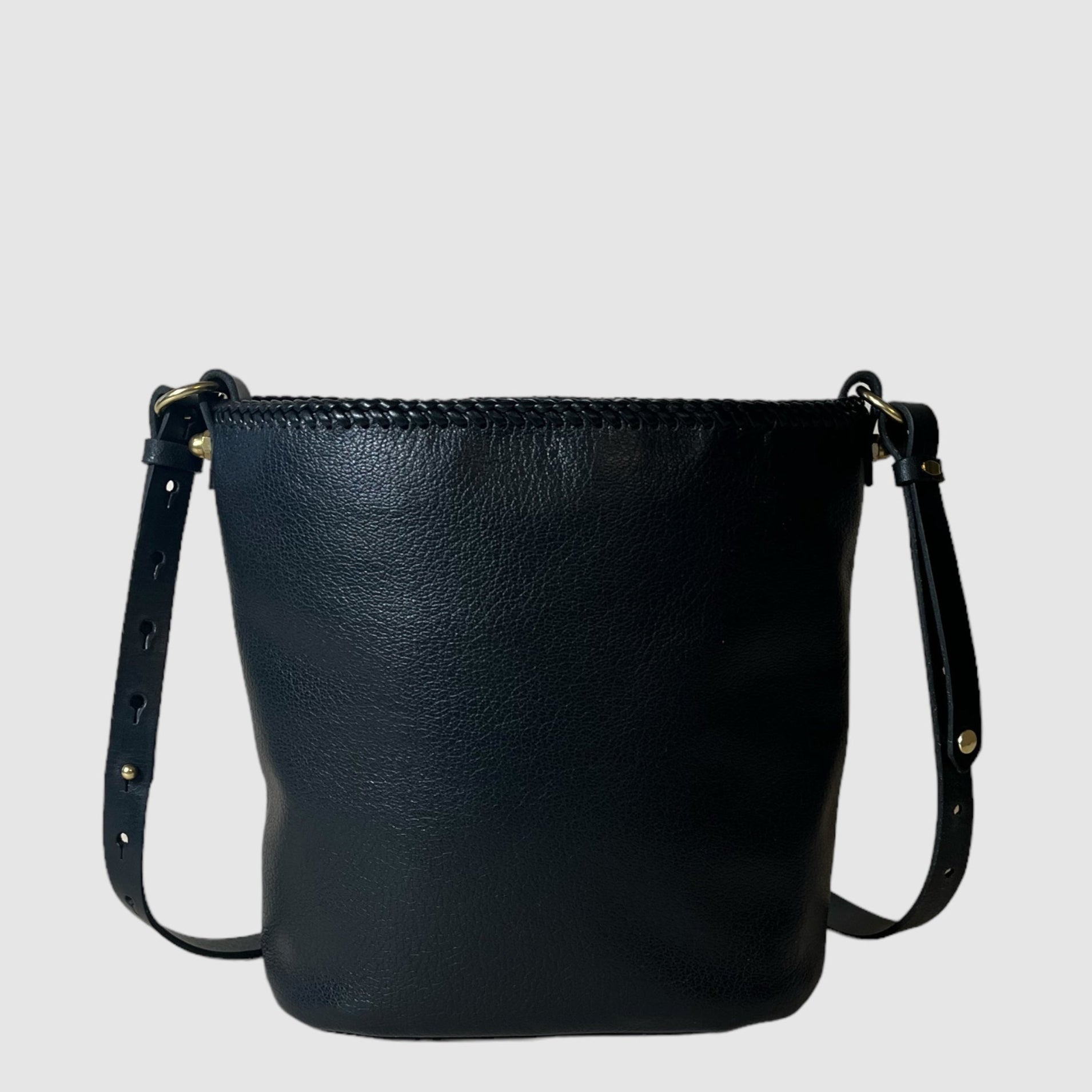 A charcoal gray bucket bag with black leather lacing and an adjustable leather strap, displayed against a plain background.