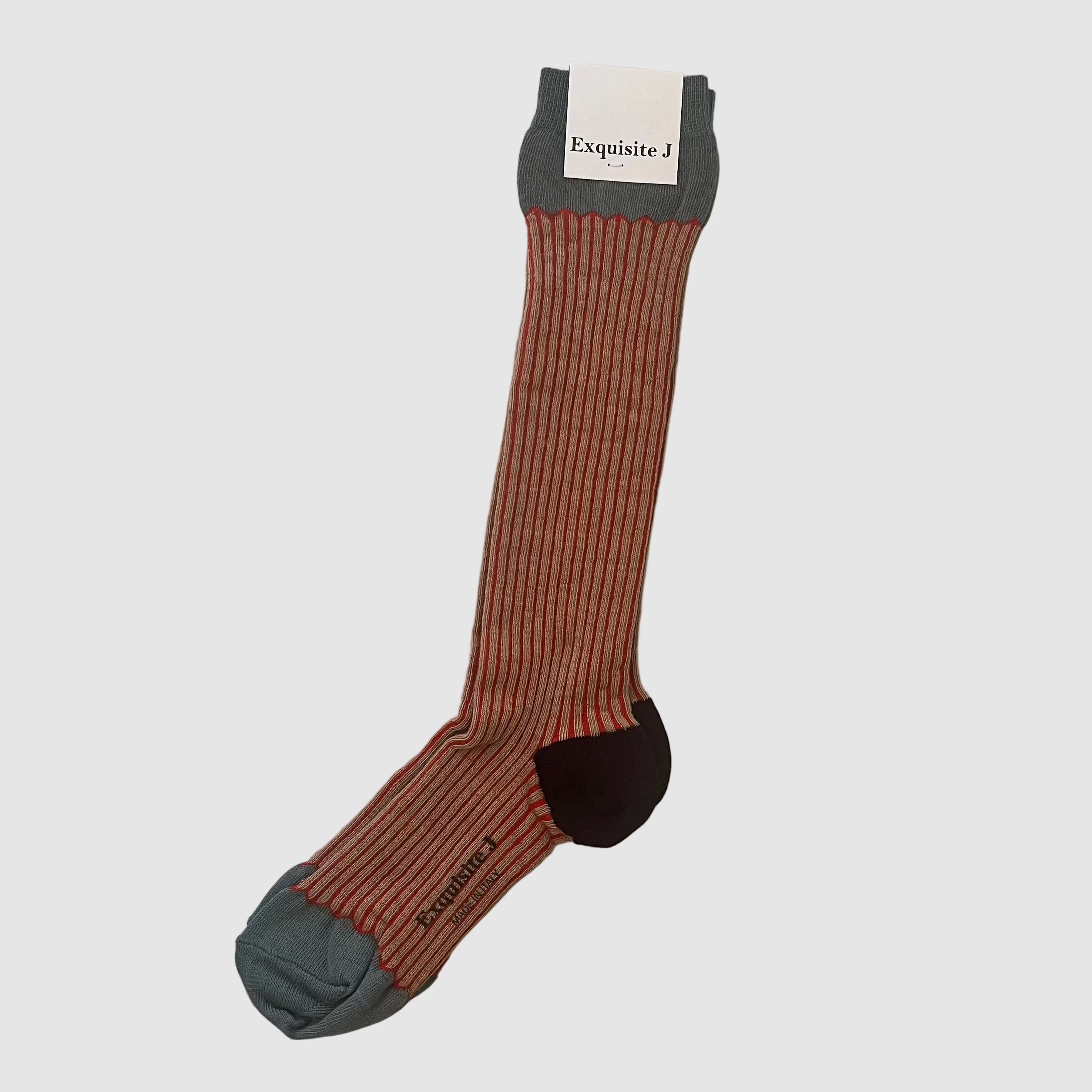 A single ribbed crew sock hanging on a white refrigerator door. The sock has a rust-orange and dark gray vertical stripe pattern, with a solid dark gray heel and sole, and a dark brown toe cap.