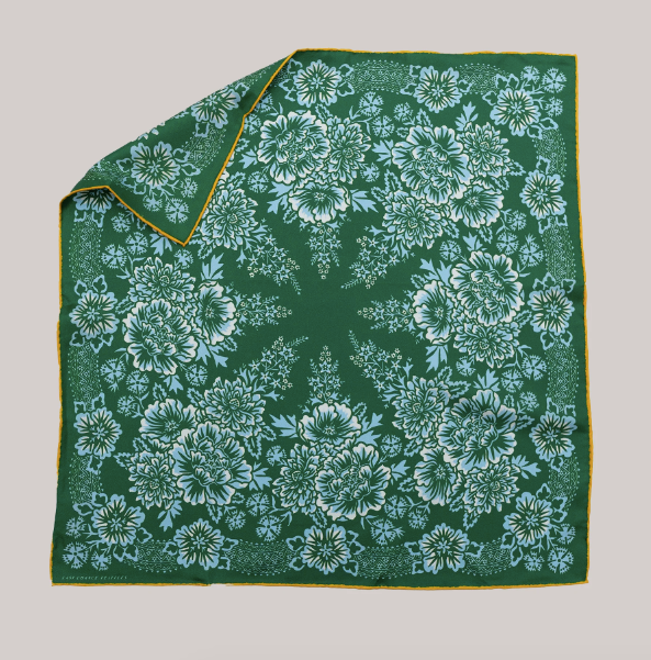 green bandana with yellow trim and 8-pointed, symmetrical, floral design in white and light blue on top. 