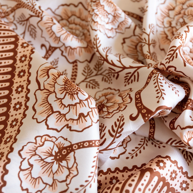 white bandana with sand and dark brownish red, geometric, floral design printed on top. 
