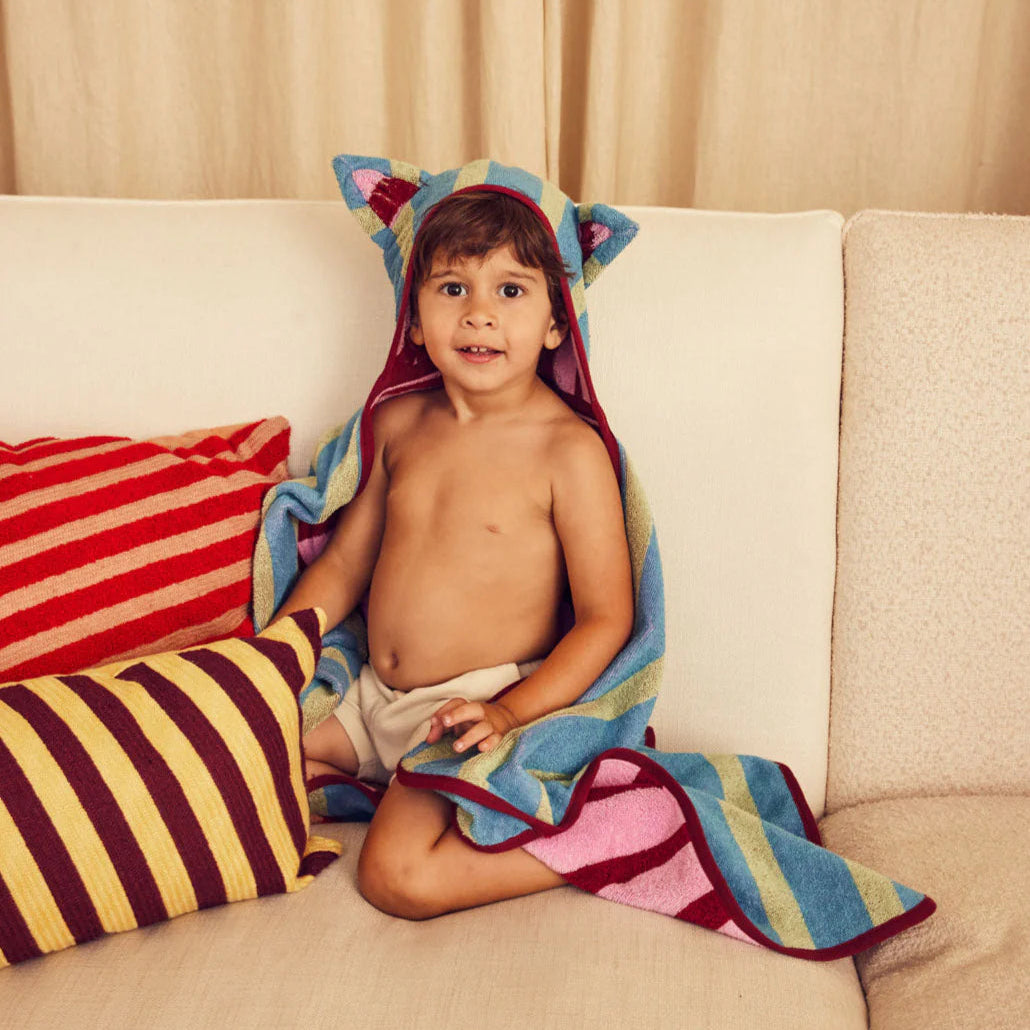 Child sitting on a couch with a colorful towel draped over them