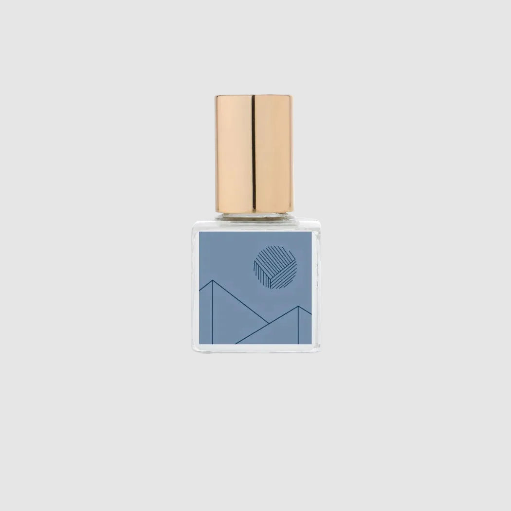 Small perfume oil bottle with a gold cap on a light grey background