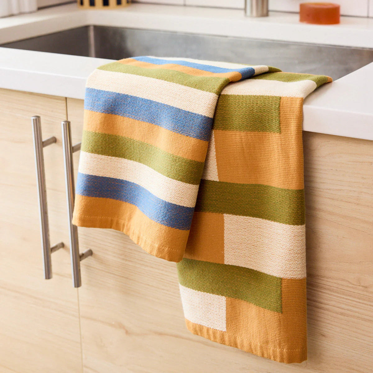 Colorful striped towel hanging on a kitchen cabinet