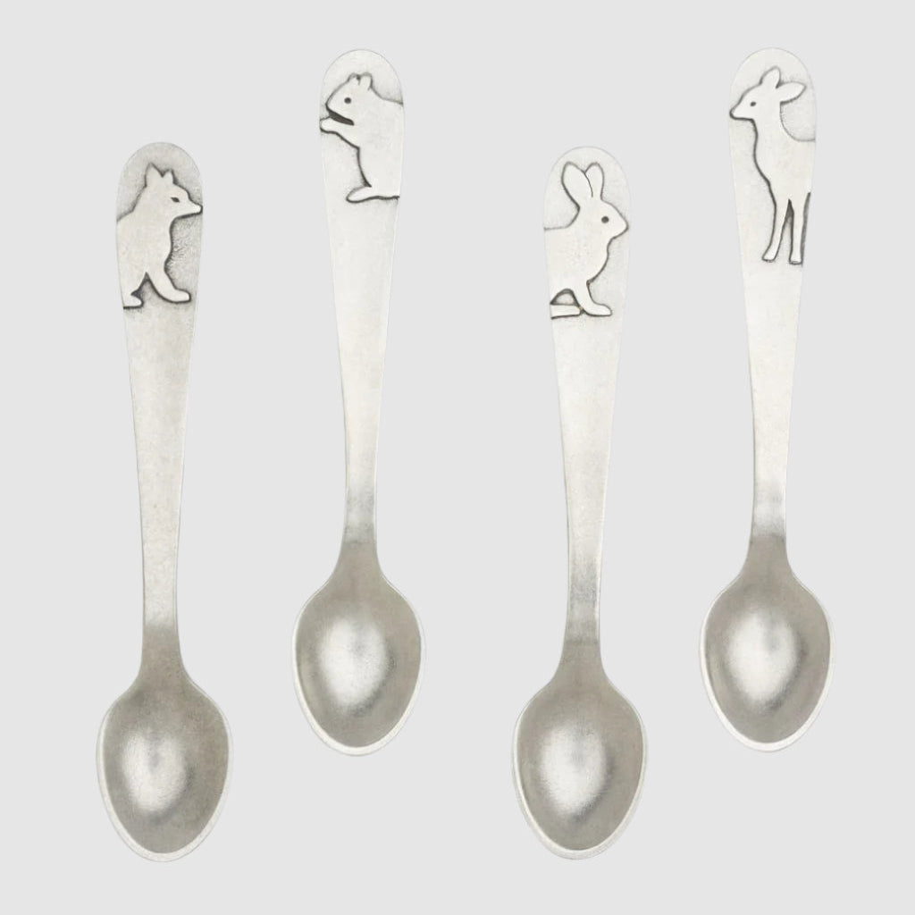 Four silver spoons with animal designs on a light gray background