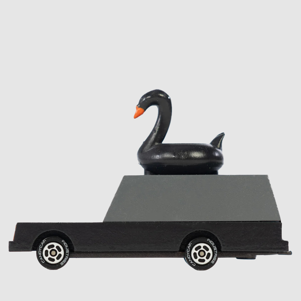 Black swan wagon of candylab cars, handmade wooden toys for kids, on a light grey background