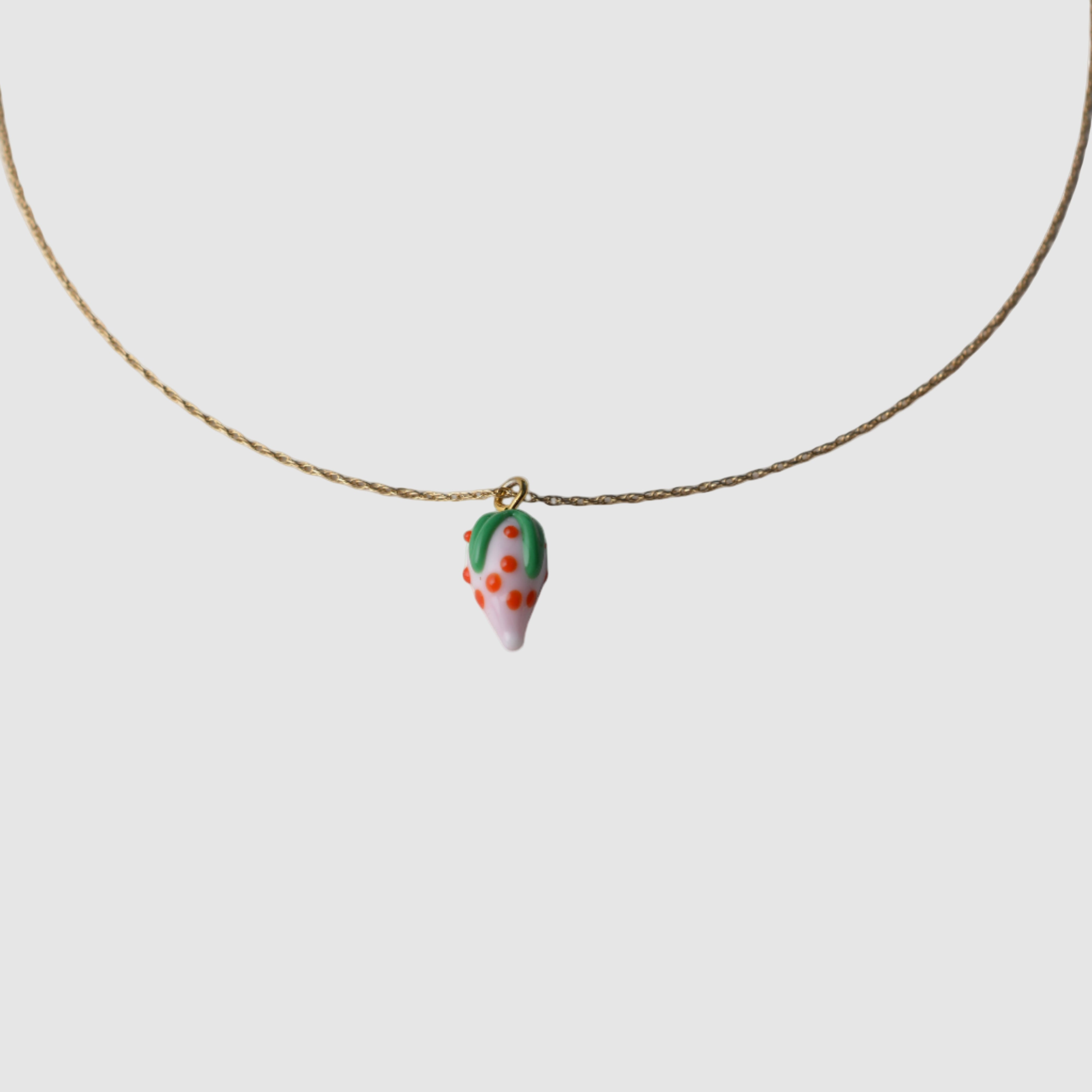 Necklace with a small  glass strawberry pendant on a plain background