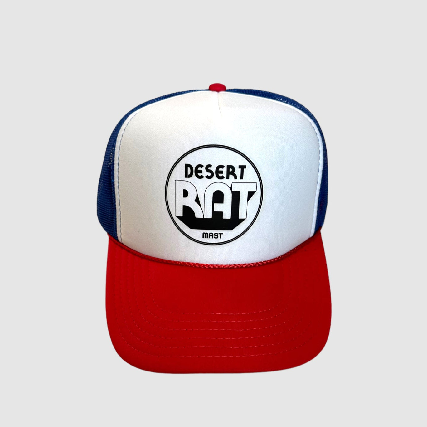 Front view of a "desert rat" logo printed in black on white trucker hat with red bill and blue mesh backing. Light gray background.