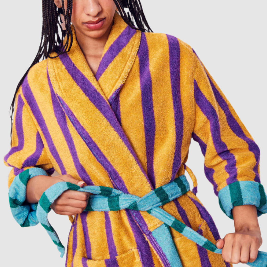 Person wearing a yellow and purple striped robe with a green belt against a white background