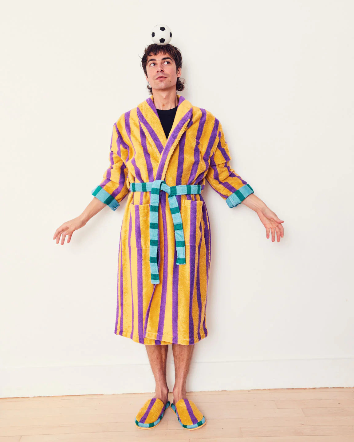 Person wearing a colorful striped robe and slippers on a white background