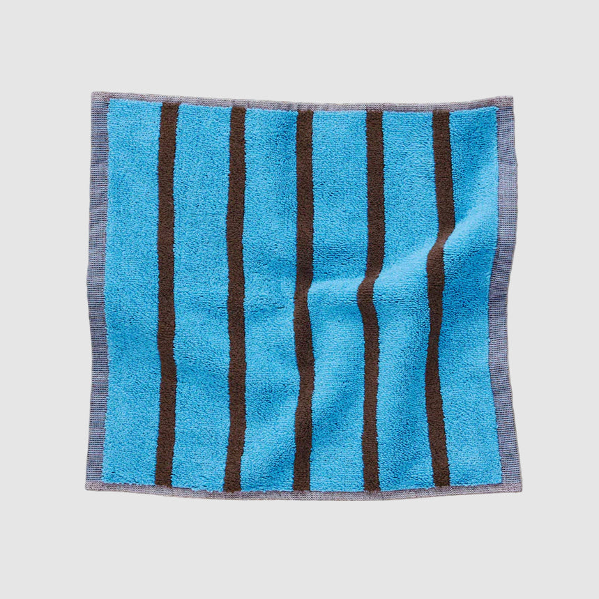 Blue and brown Dusen Dusen striped wash cloth on a light grey background
