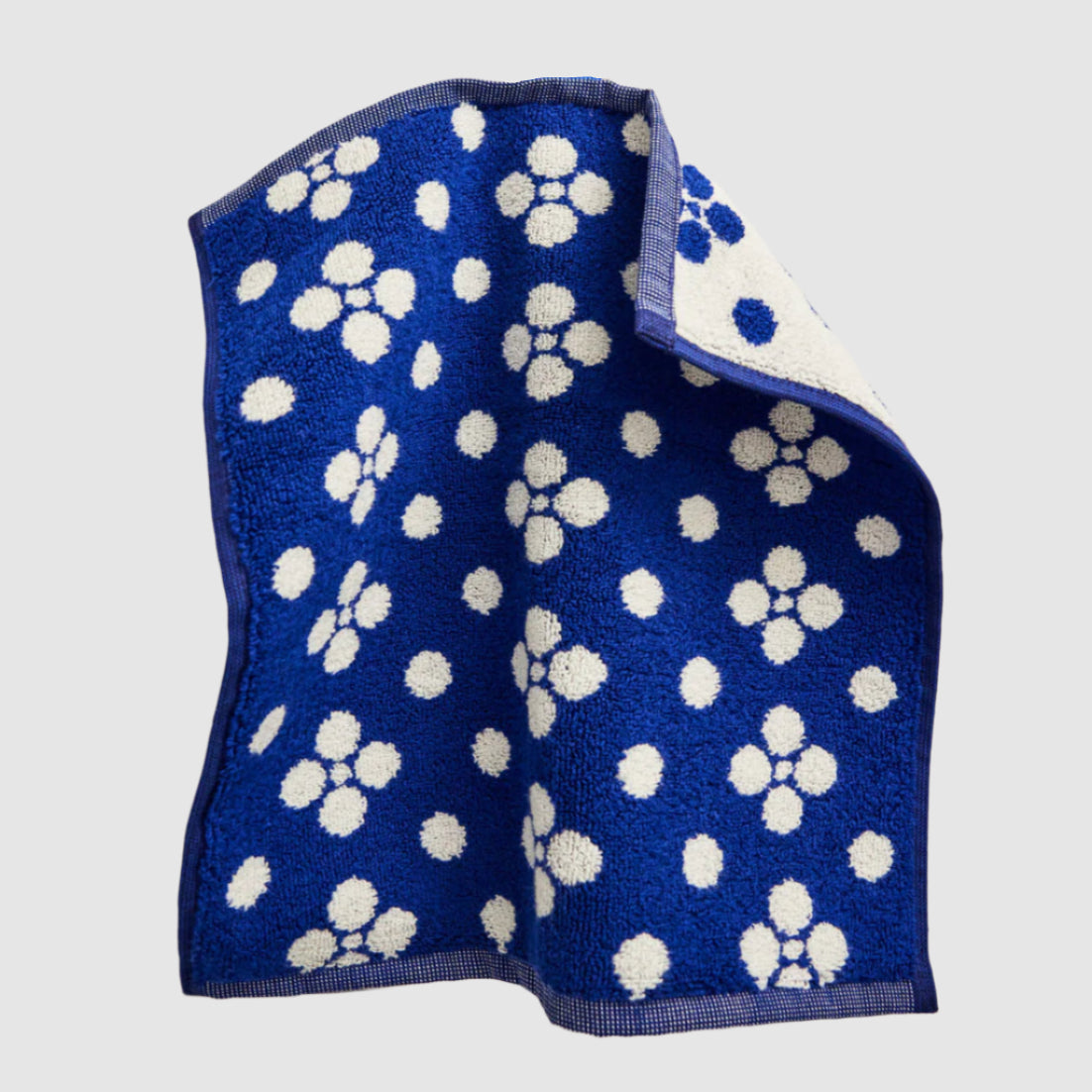 Blue towel with white dot prints hanging on a tiled wall