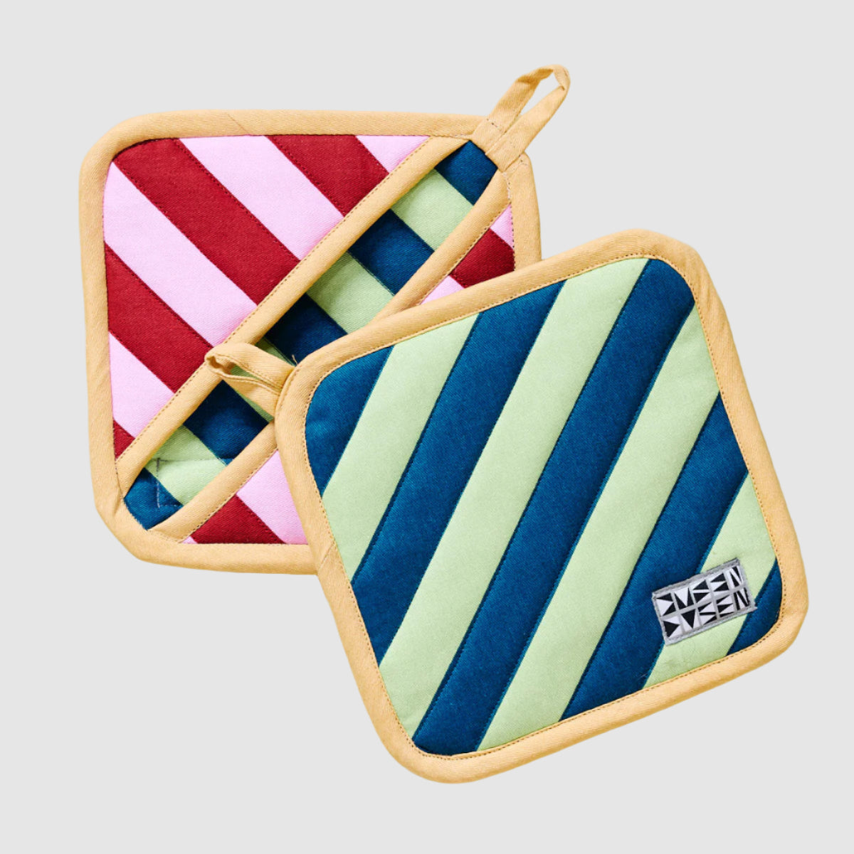 Two square Dusen Dusen pot holders with contrasting striped patterns on a light grey background