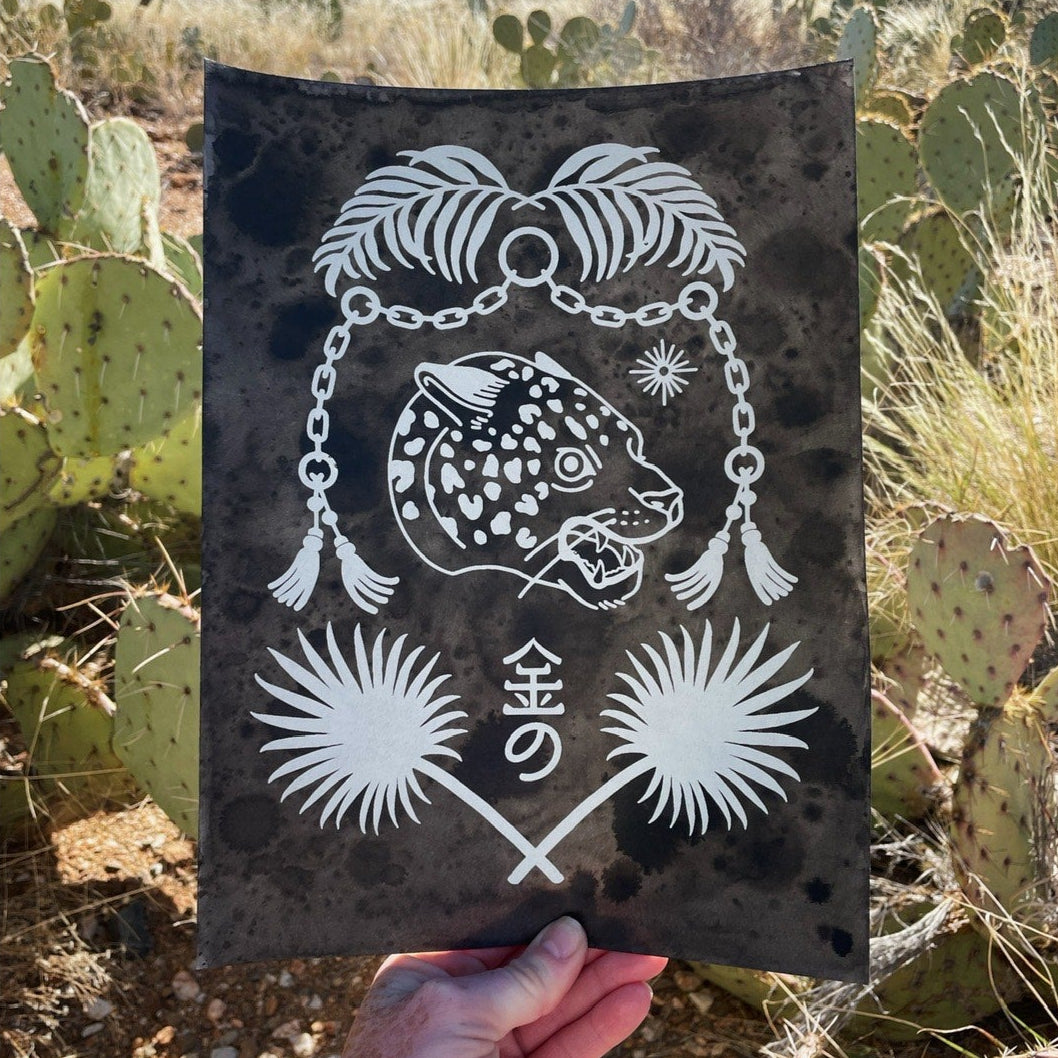 Hand holding a black and white decorative item with a desert landscape in the background
