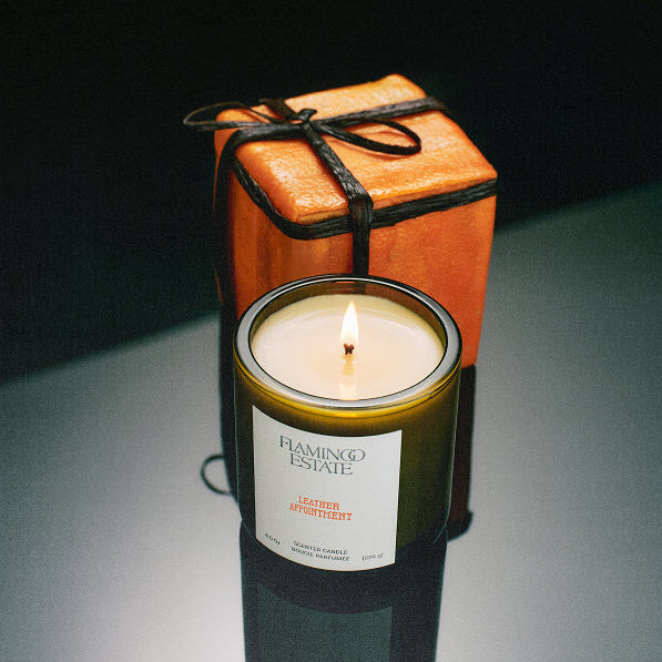 Candle in a decorative container with a gift box on a dark background