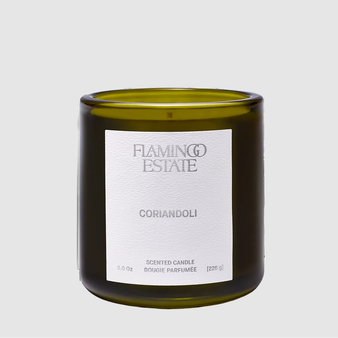 Green candle with a white label reading "CORIANDOLI" and Flamingo Estate brand on a light gray background