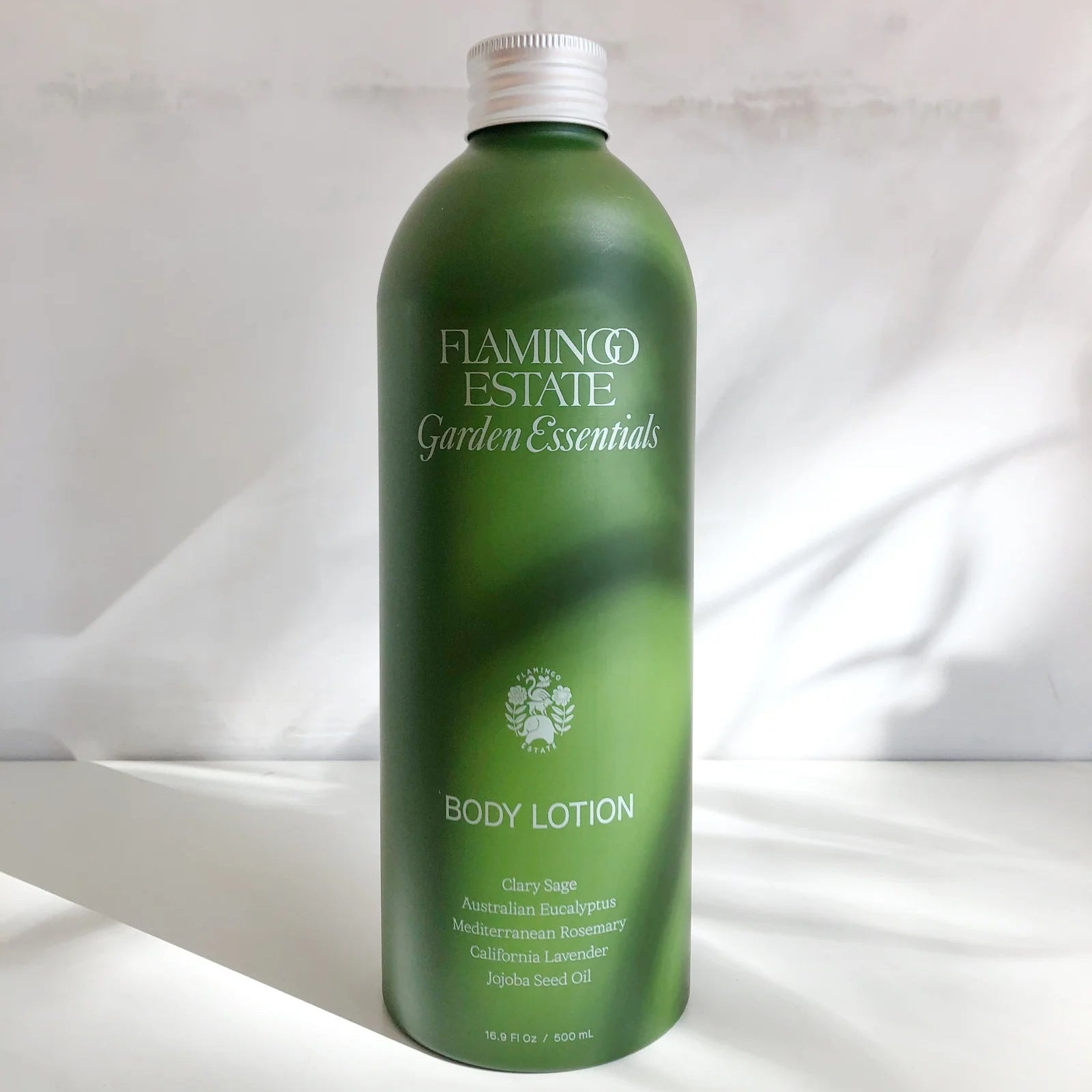 Green bottle of Flamingo Estate Garden Essentials Body Lotion on a white background