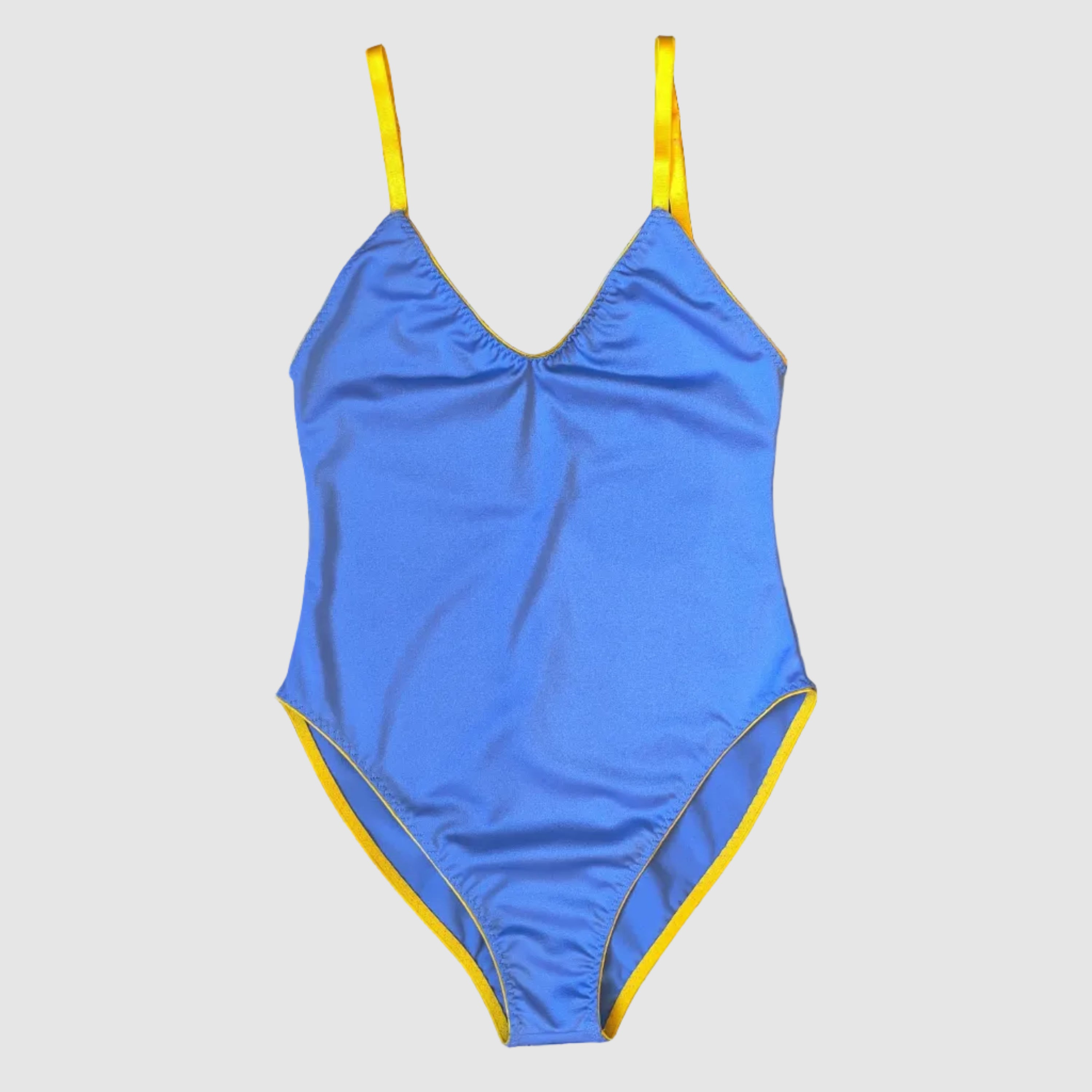 A blue one-piece swimsuit with yellow trim and shoulder straps, laid flat on a dark purple and white striped fabric background.