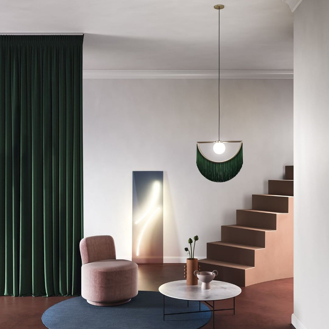 Modern interior with a pink chair, round table, and staircase.