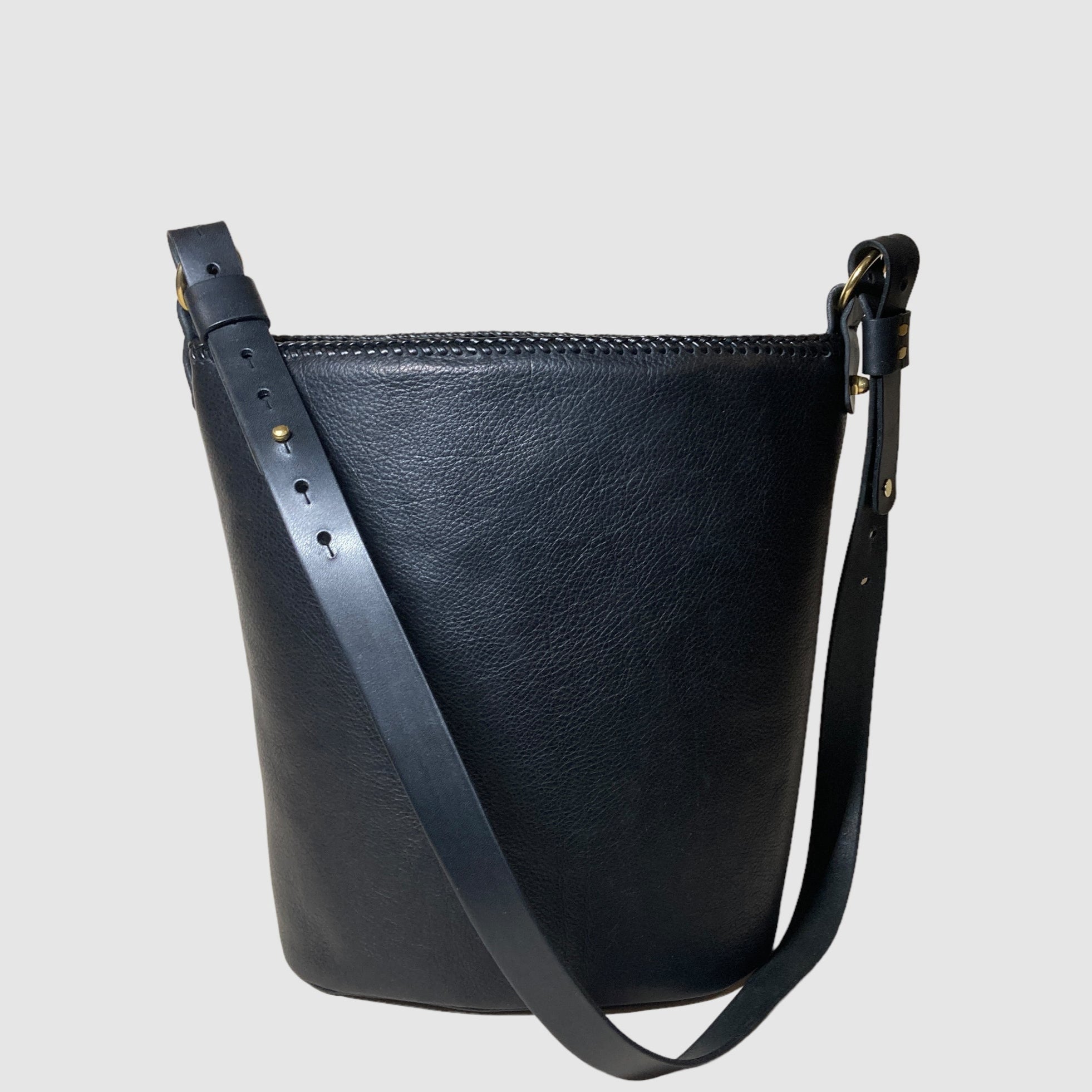 Black leather barrel bag with a shoulder strap and a zipper closure at the top.