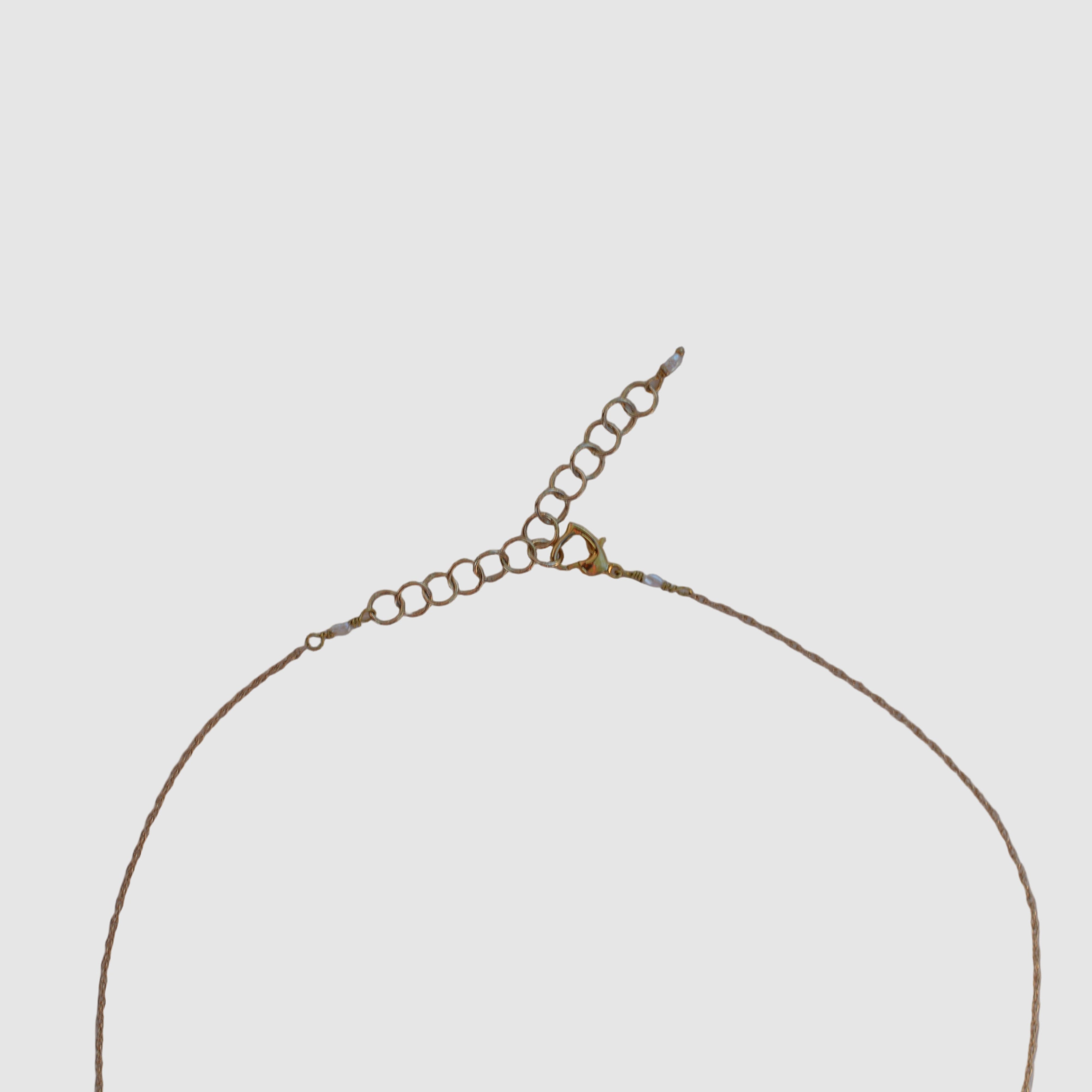 clasp view of  gold chain necklace on light grey background