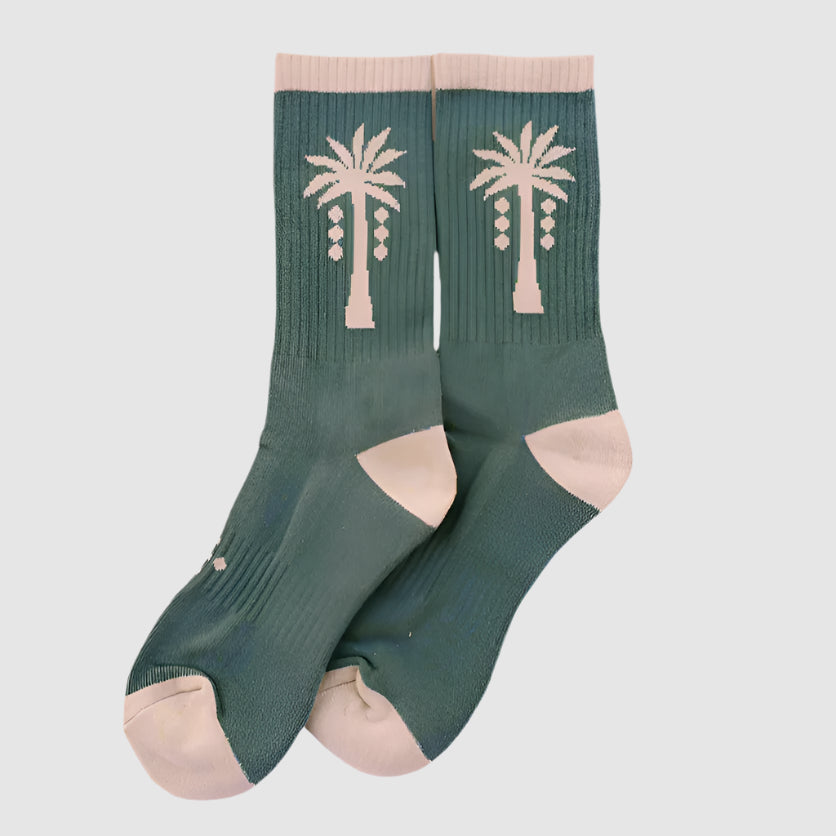 Green socks with palm tree design on a gray background