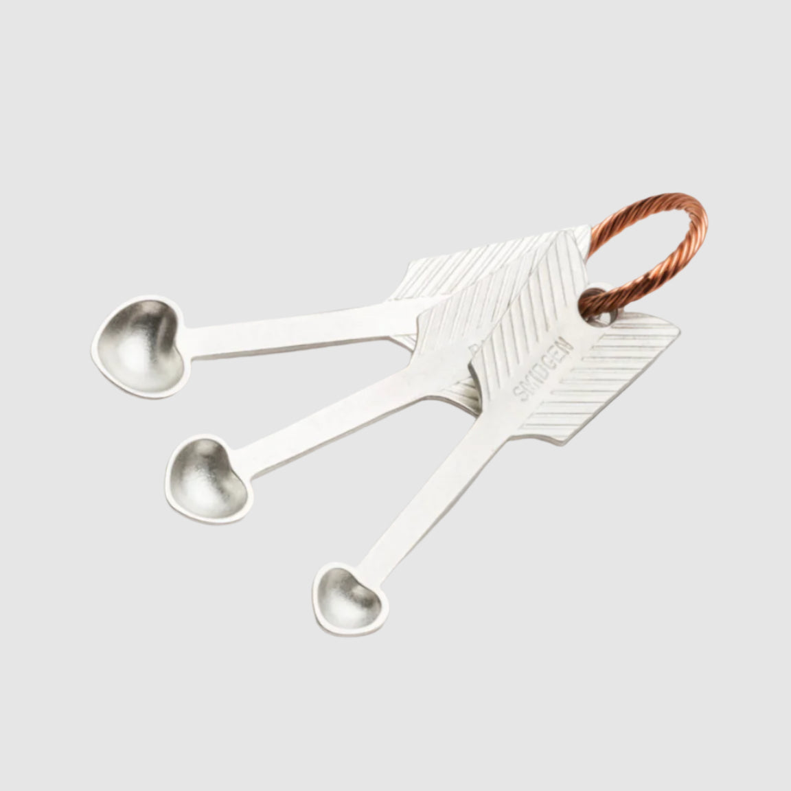 Set of silver measuring spoons with a decorative handle on a light gray background