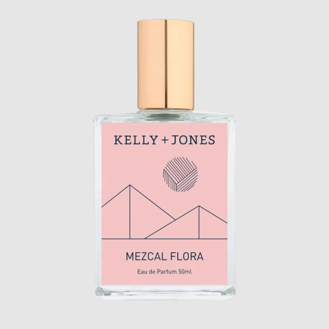A bottle of KELLY + JONES Mezcal Flora eau de parfum with a pink label and geometric designs, next to its packaging box. Found in MAST, Tucson's Scent House! This is the perfect gift for yourself of someone else to find during the Tucson Gem Show