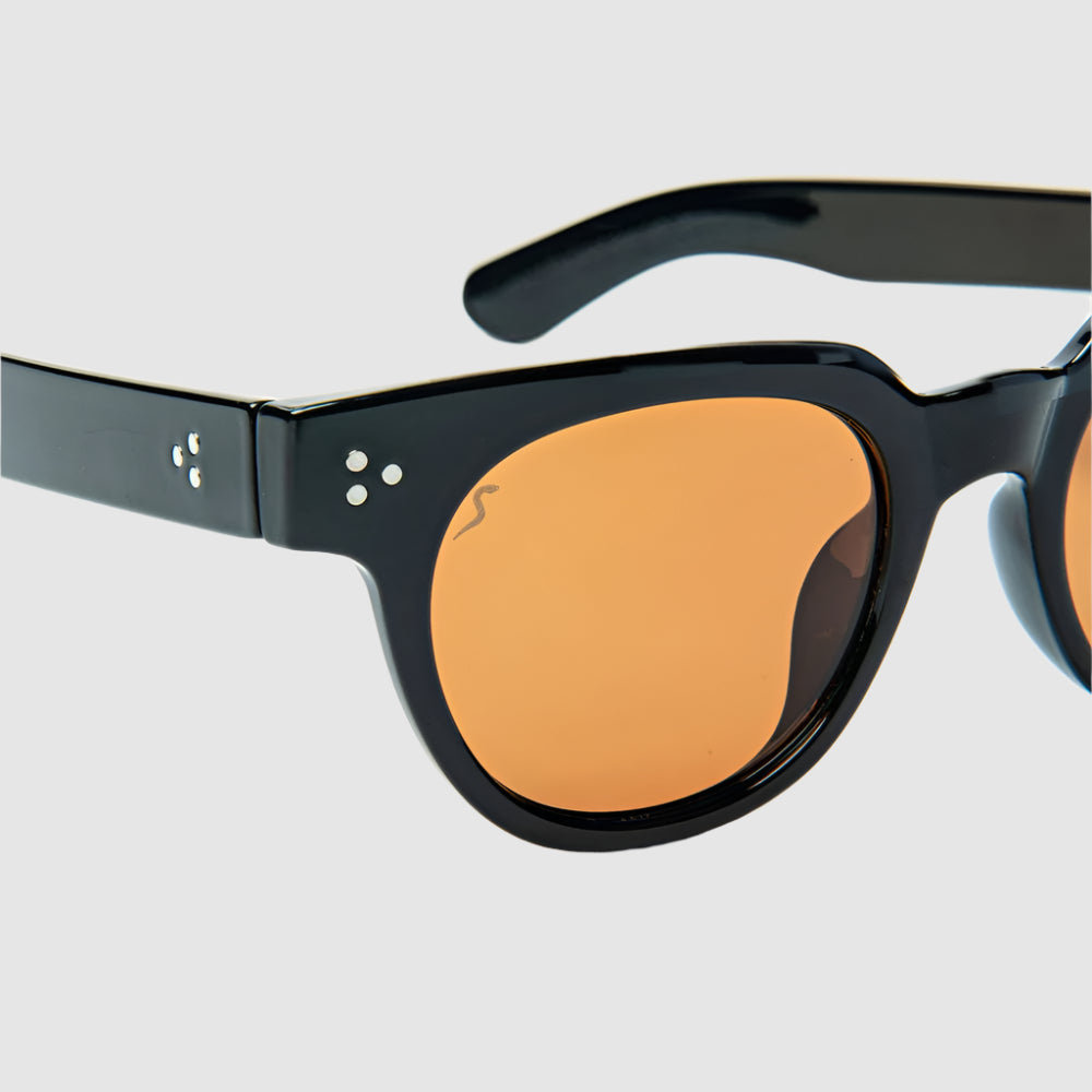 Close-up, angled, front view of black and amber, 'Human Being' style, Shady Spex sunglasses on a light grey background. 