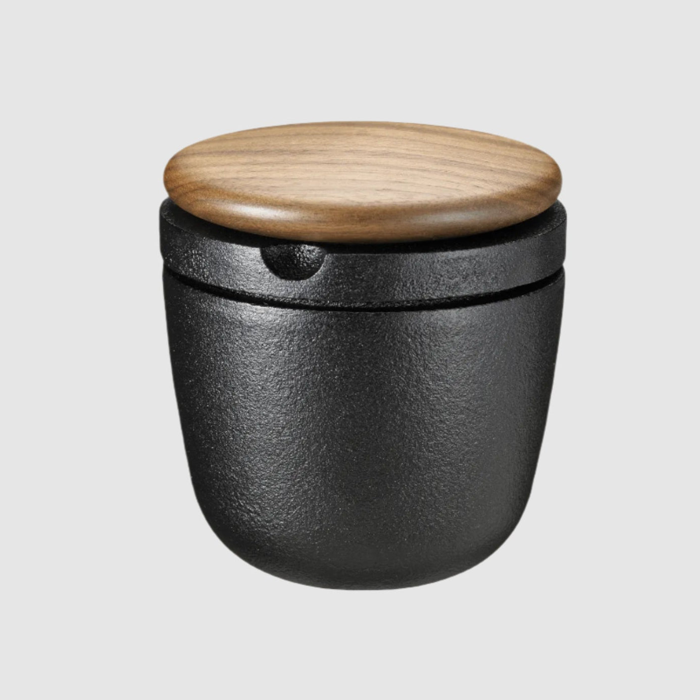 Black container with a wooden lid on a beige background