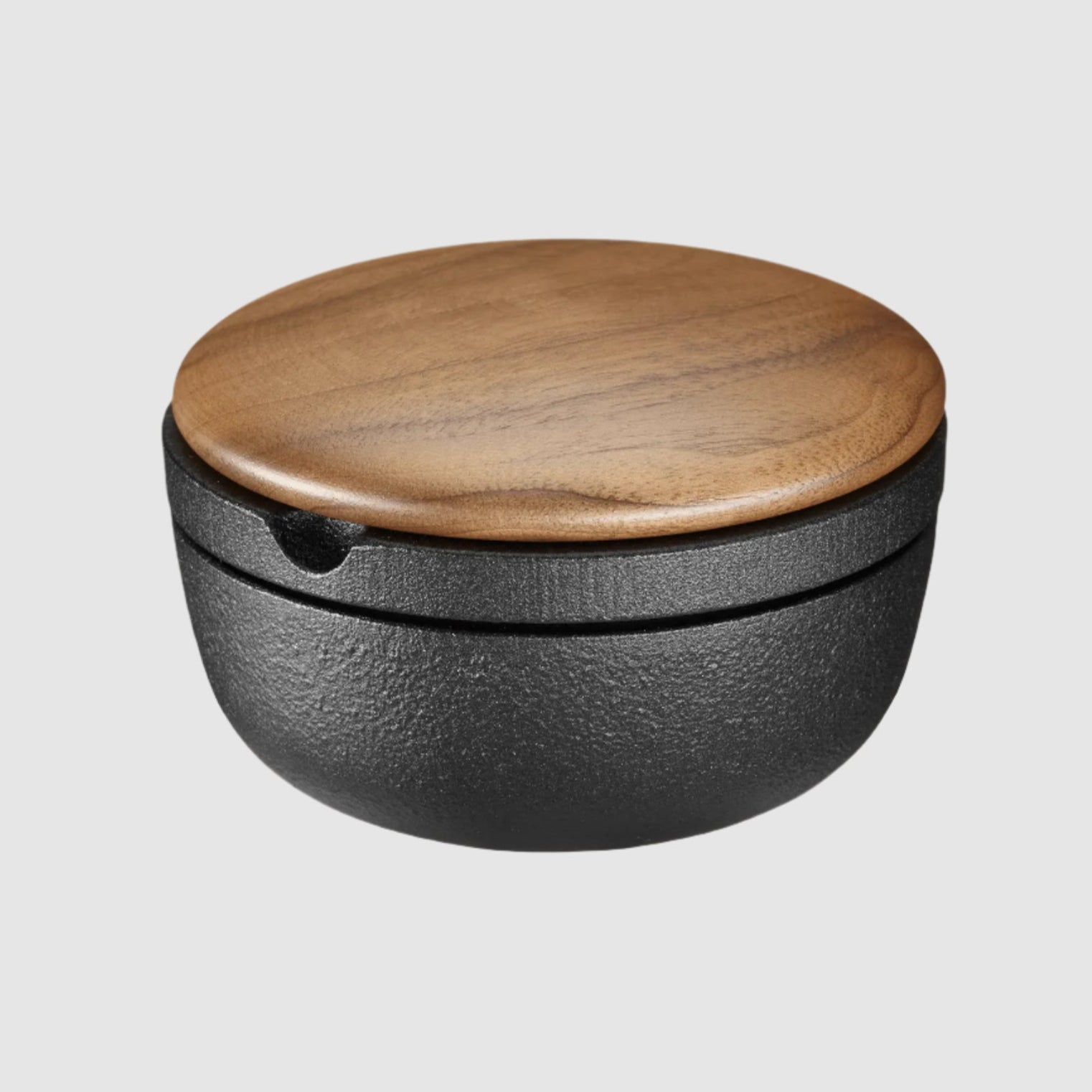 Black container with a wooden lid on a beige background