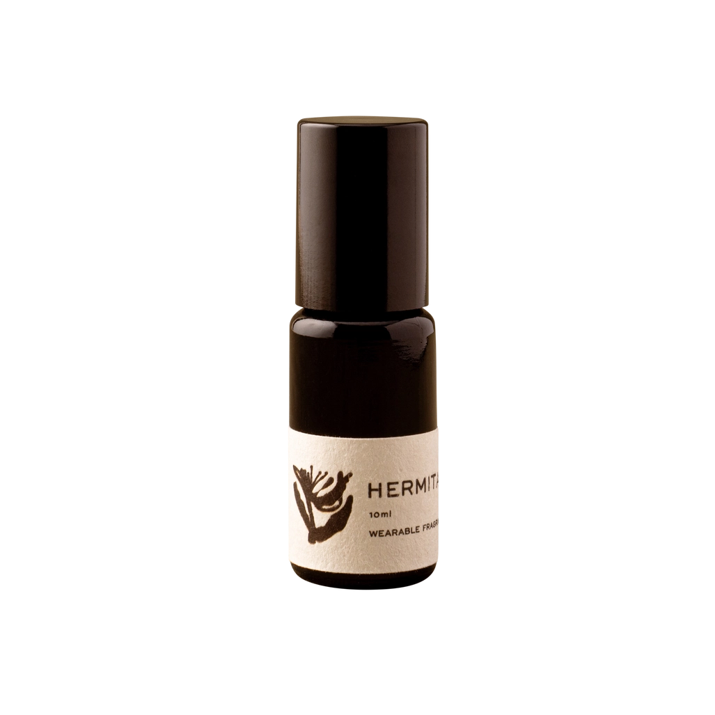 A small dark amber glass roll-on bottle with a cream label reading HERMÈT PARIS, centered on a solid white background.