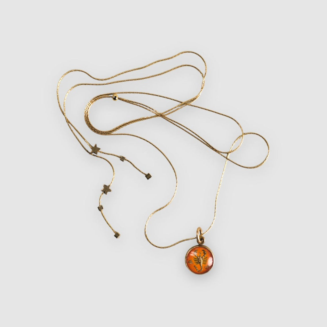 Vintage 1950's German Scorpio Intaglio pendant necklace set in brass, on a gold-filled snake chain with an adjustable clasp, finished with tiny brass star accent beads.