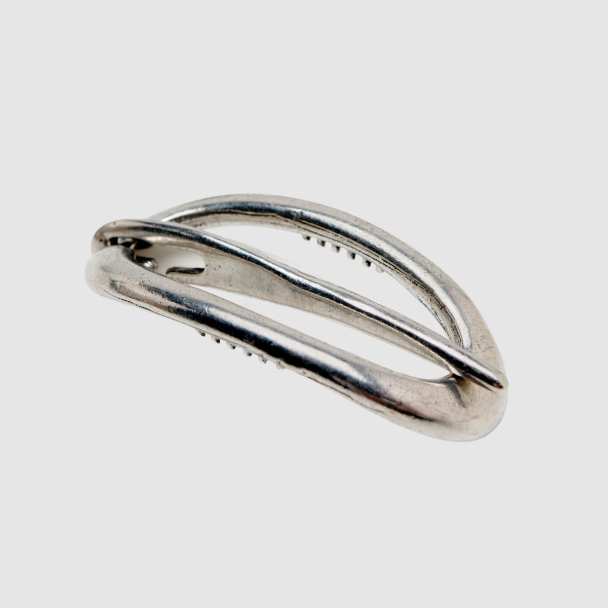 A single pewter Danish hair clip on a light grey background