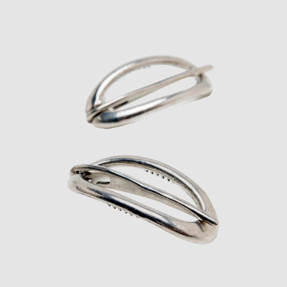 A pair of pewter Danish hair clips on a light grey background