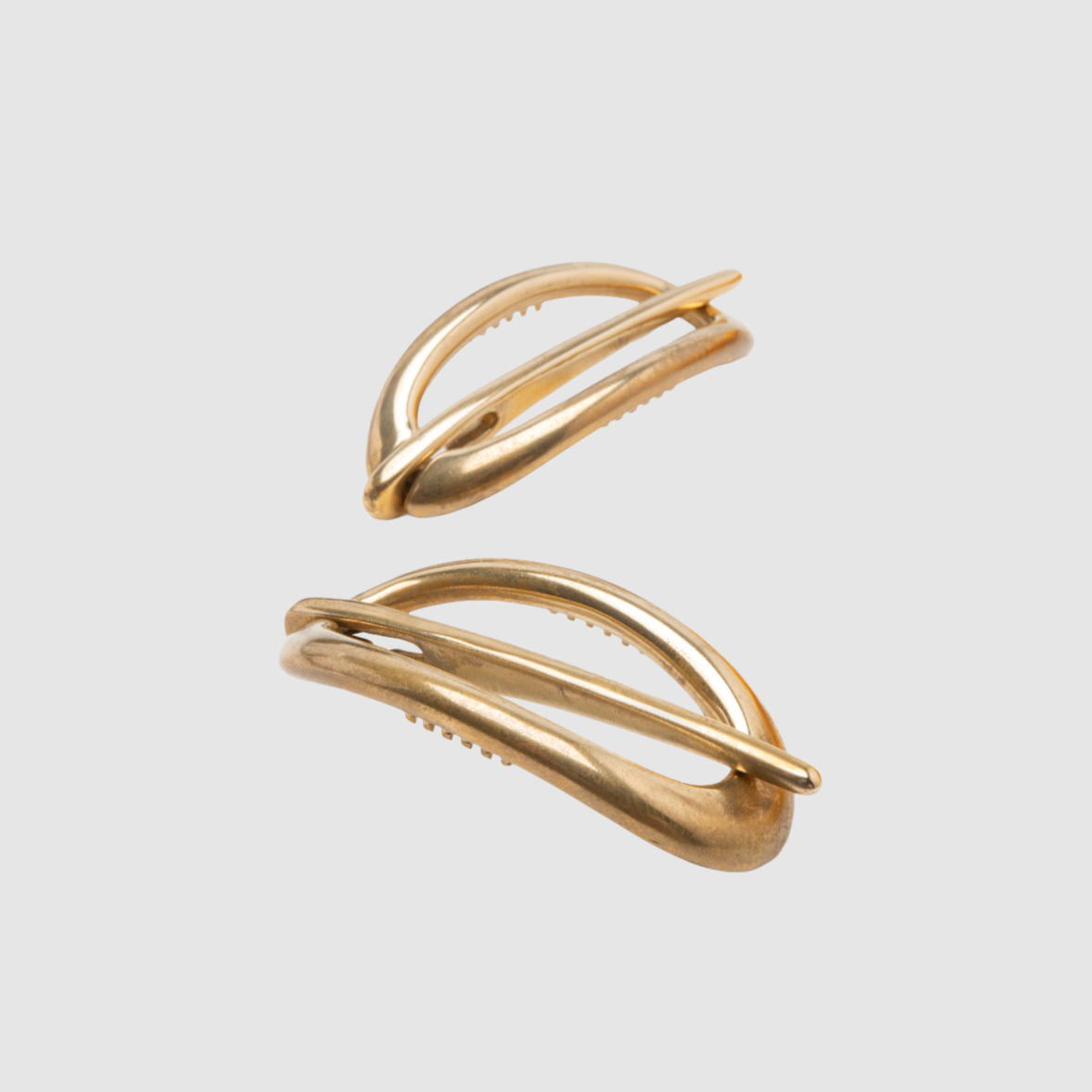 A pair of bronze Danish hair clips on a light grey background
