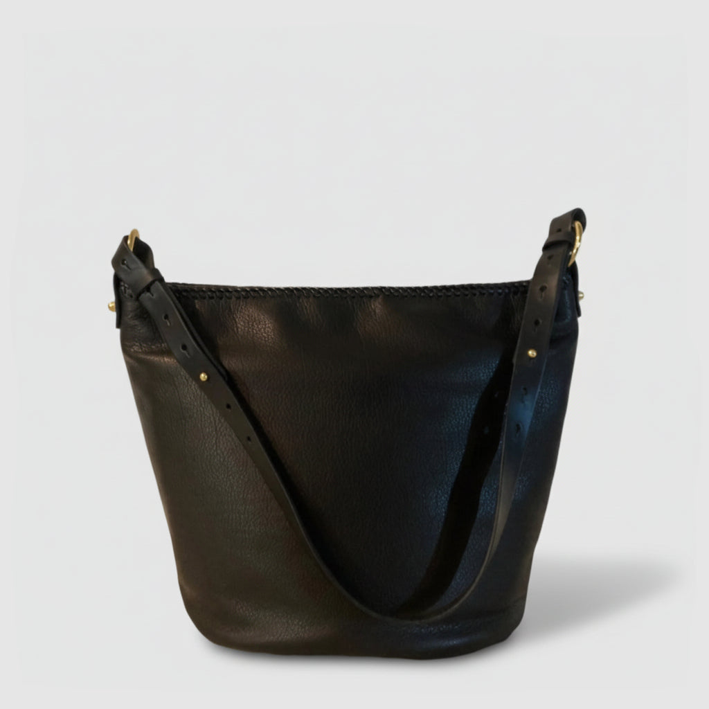 Black leather handbag with gold accents on a light gray background