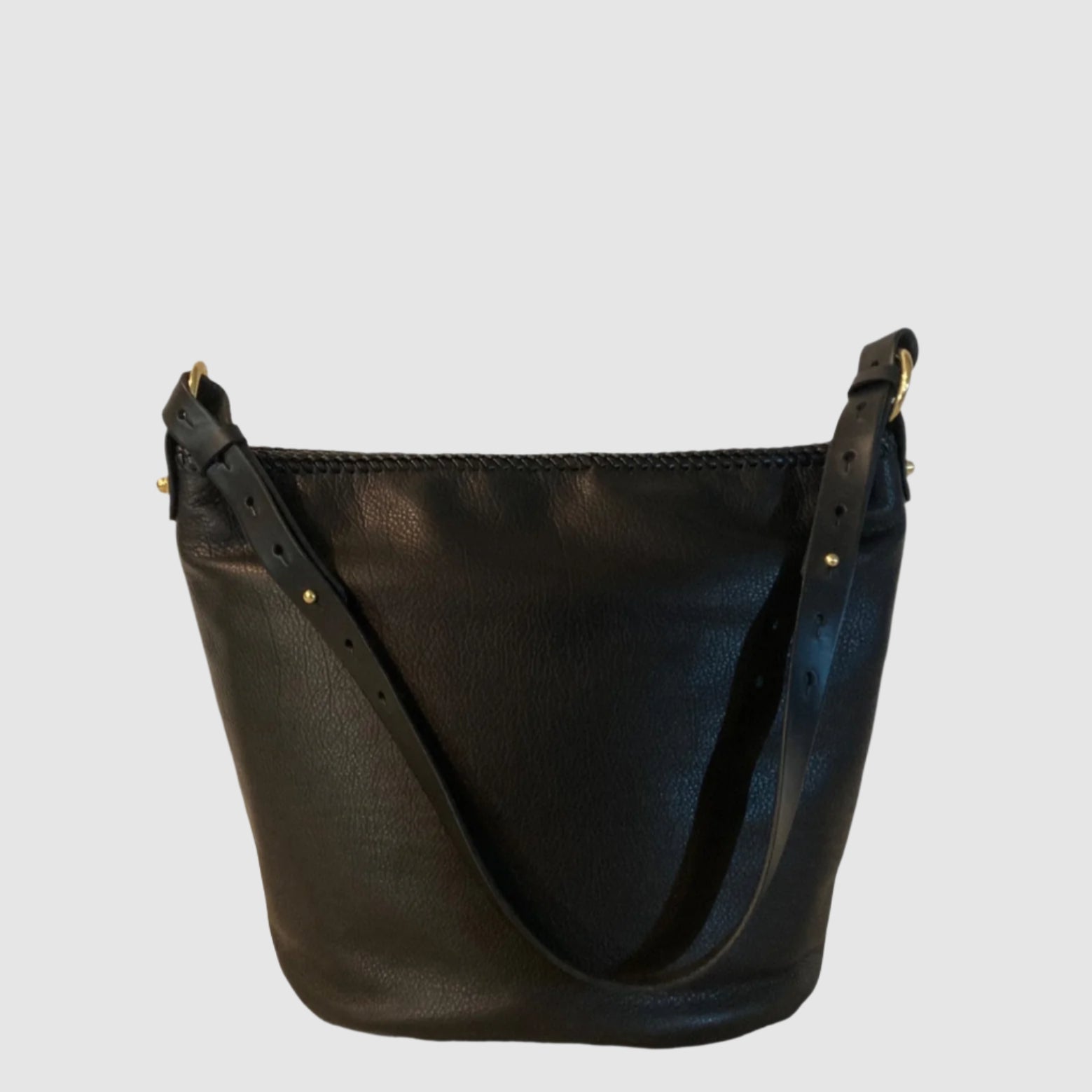 Black leather handbag with gold accents on a light gray background